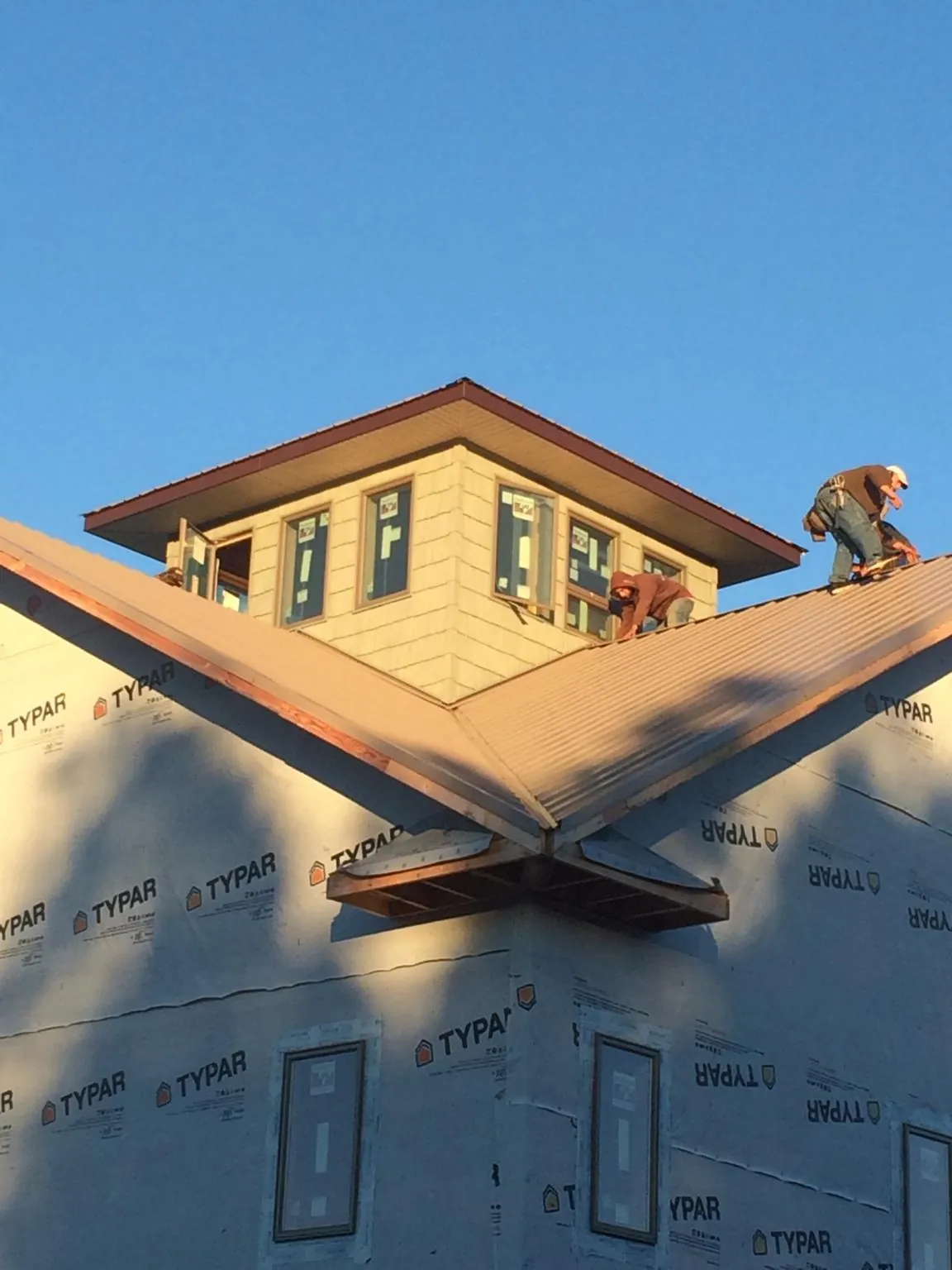 Roofers working around a rooftop cupola on a new metal roof at sunset — Roof Waterproofing in Belfast by Roofing Brothers
